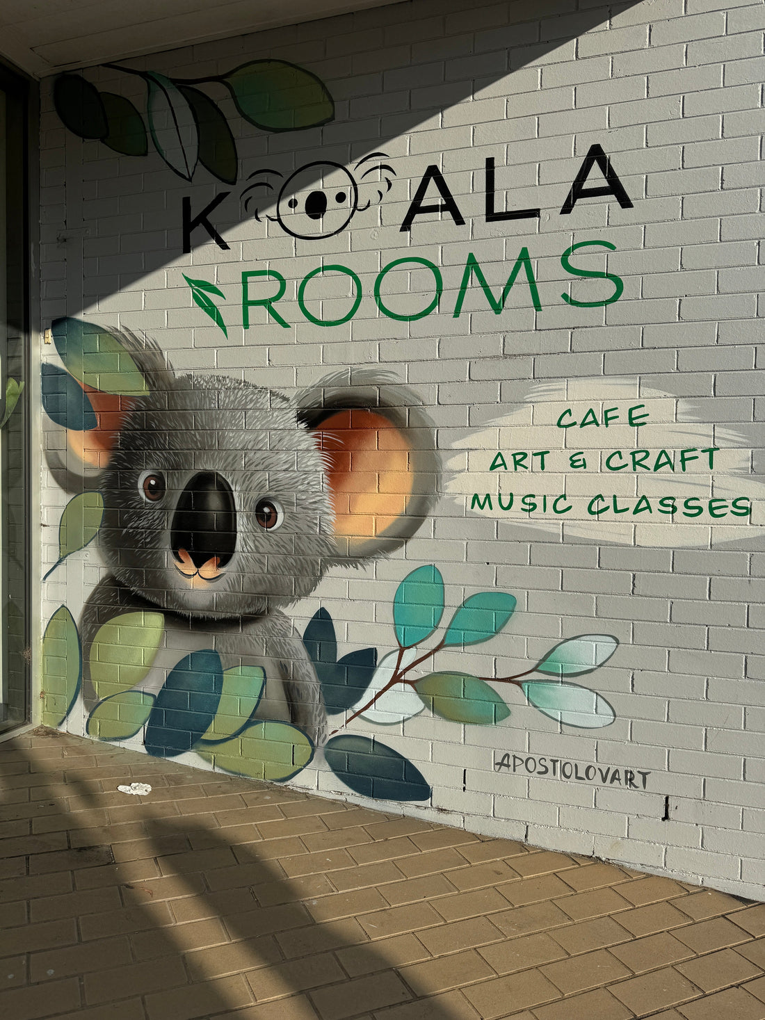 painting of a koala with green leaves, outside of a store